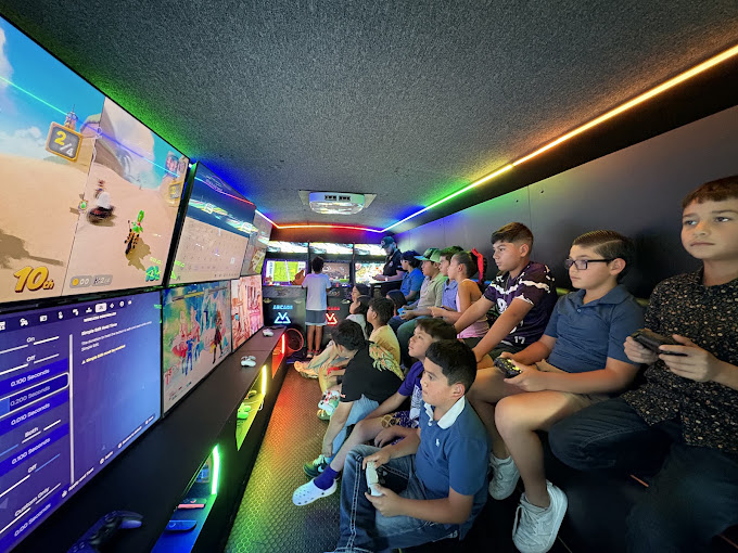 Kids seated along the screen wall playing together inside the RGV Games on Wheelz gaming bus