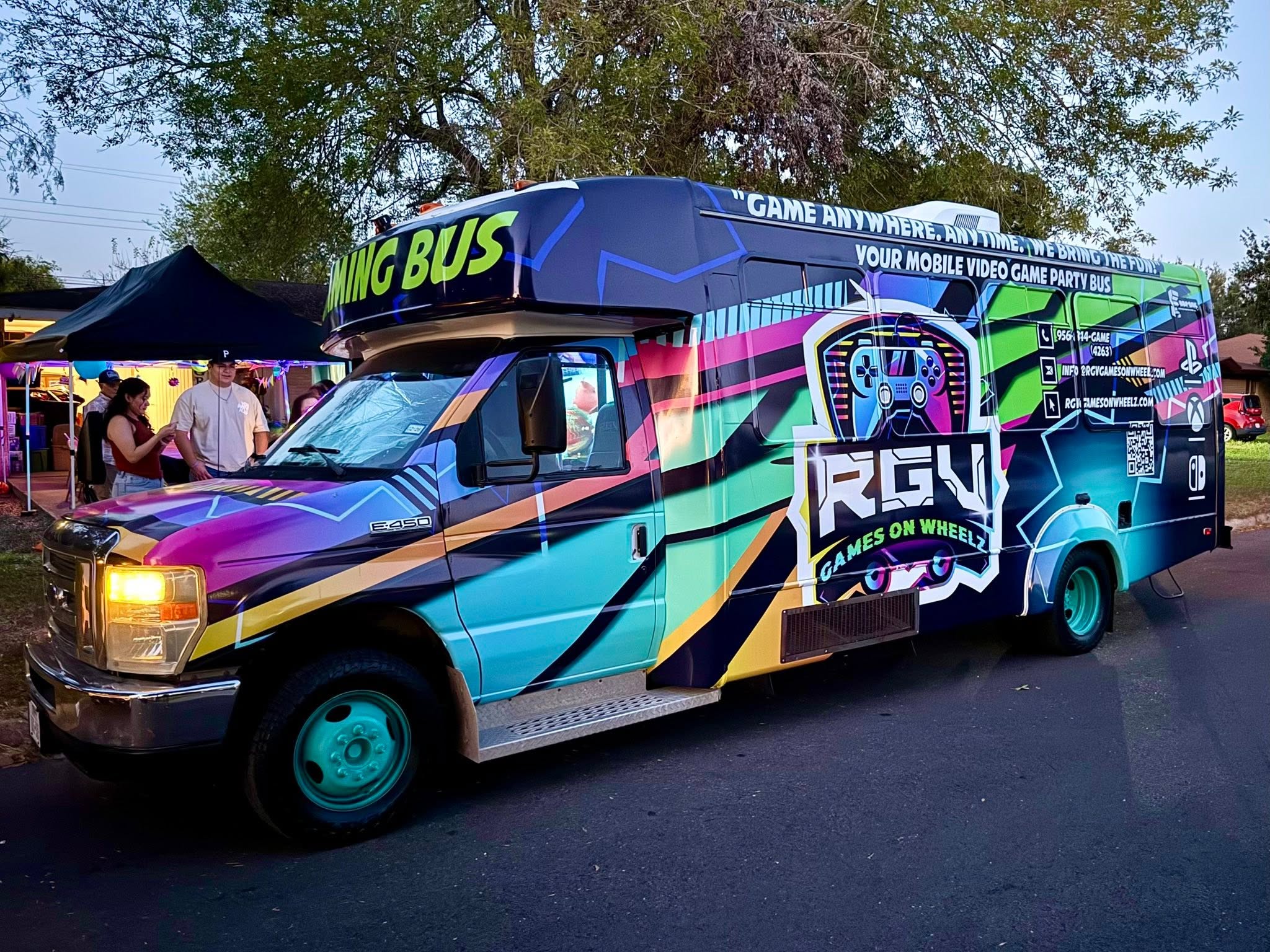 The RGV Games on Wheelz gaming bus pulled up to a Rio Grande Valley backyard party at dusk with guests gathered under a canopy